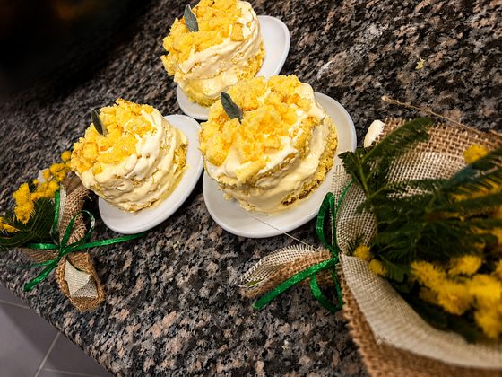 Tre tortine mimosa sul bancone di granito, con fiori di mimosa